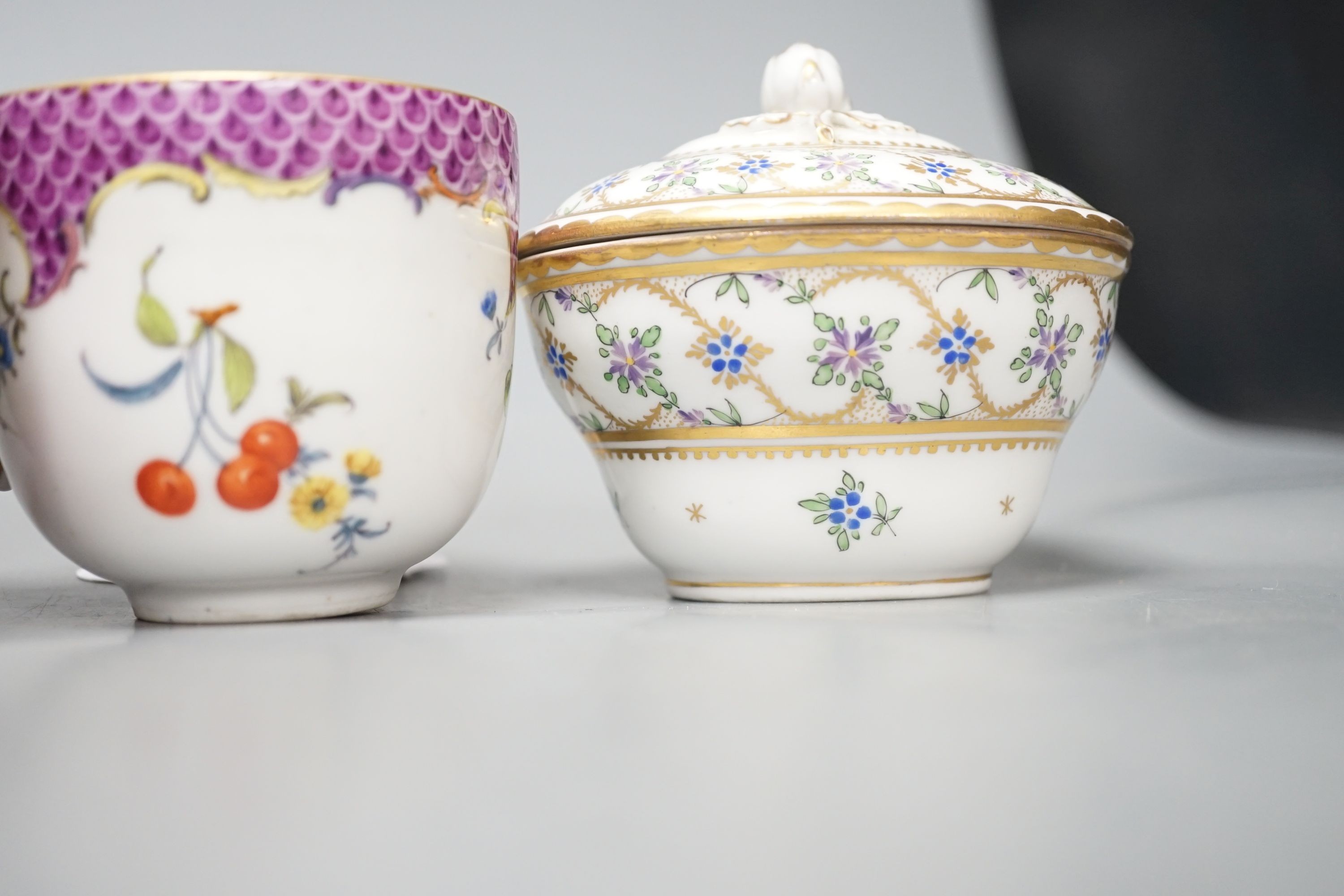 An 18th century Meissen pink ground coffee cup with entwined handle painted on two sides with a figural landscape on a pink ground, a 19th century French box and cover painted with flowers, a German coffee cup with pink